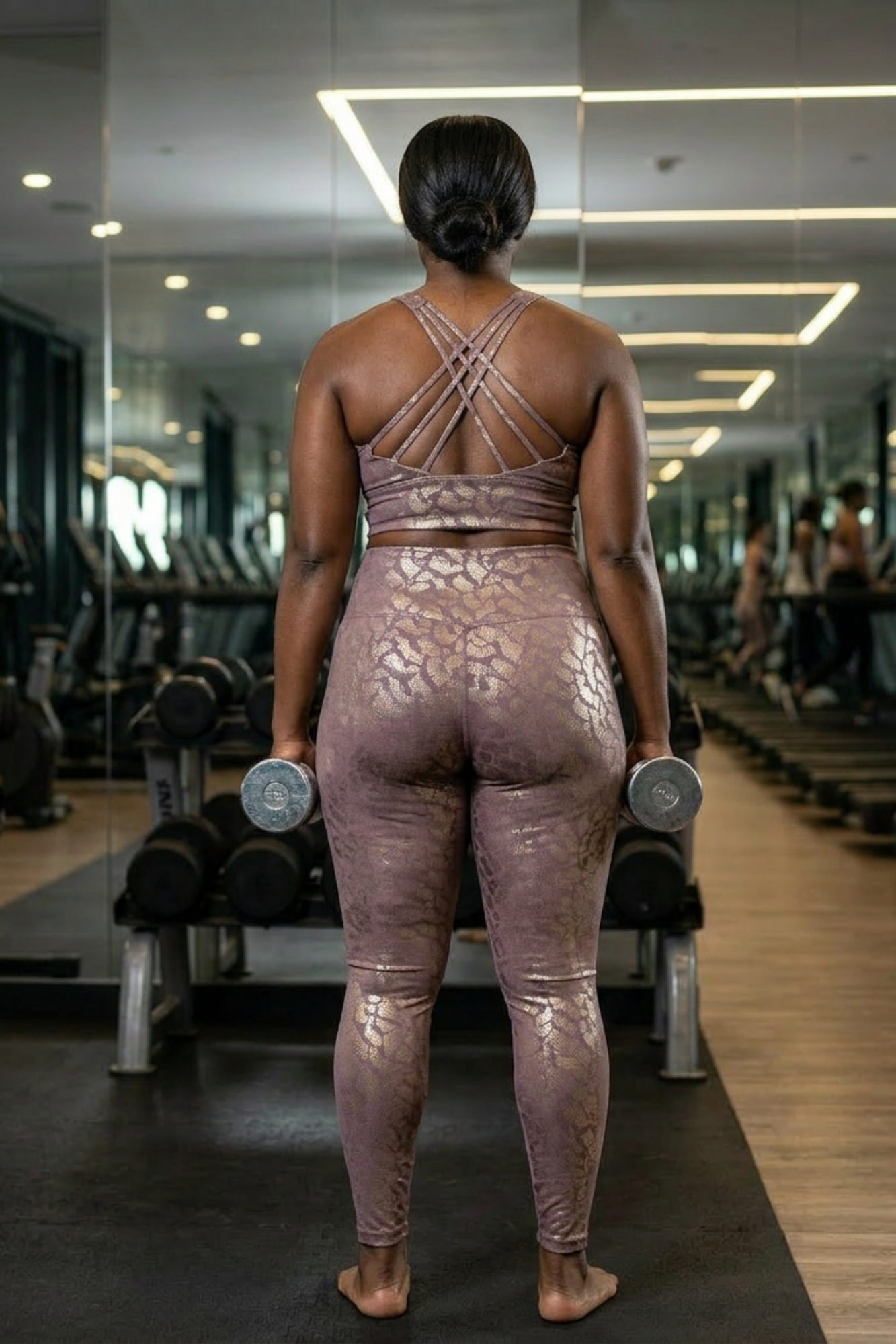 Person in a gym wearing a metallic outfit holding dumbbells.