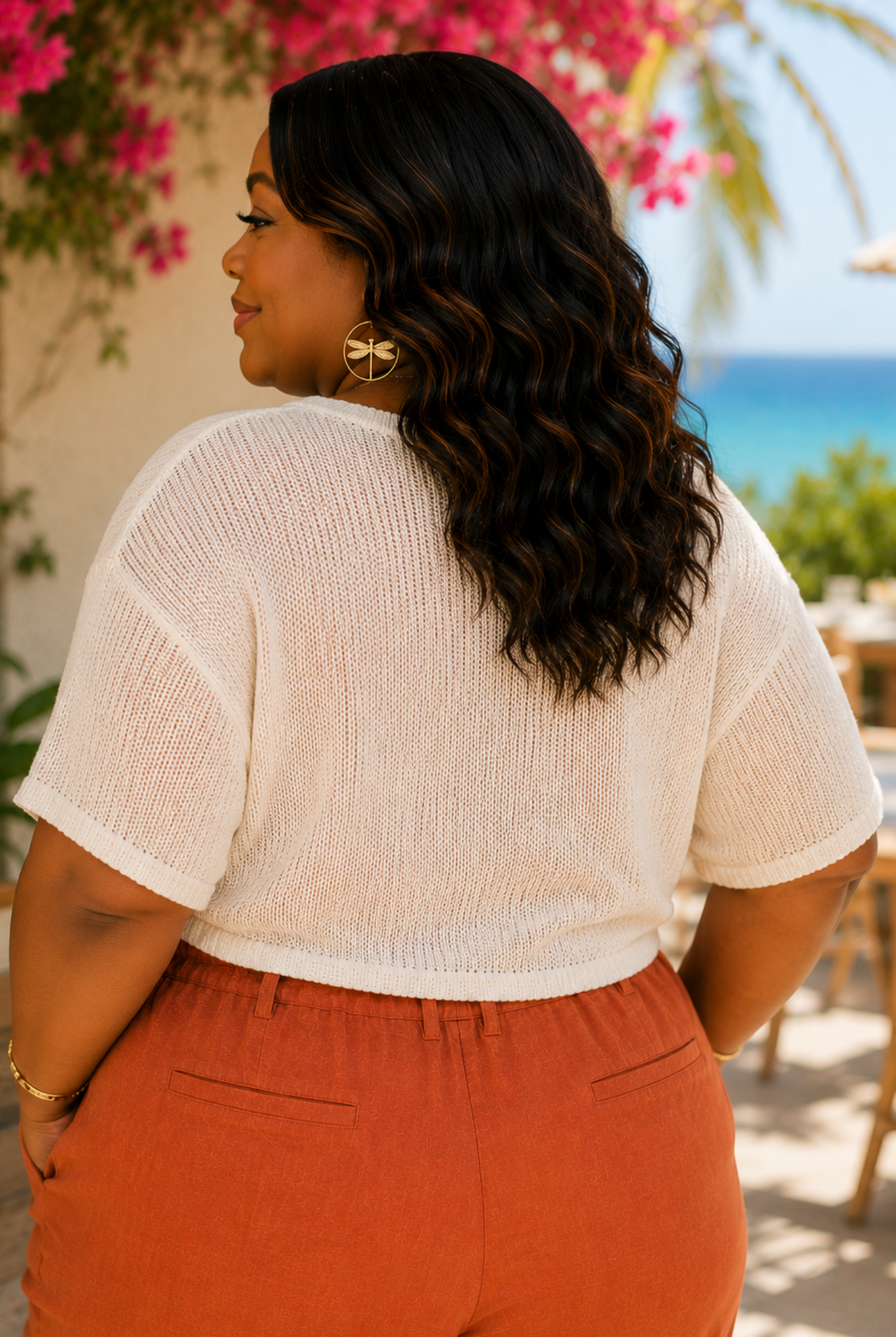 Woman wearing a white top and orange pants with a scenic background