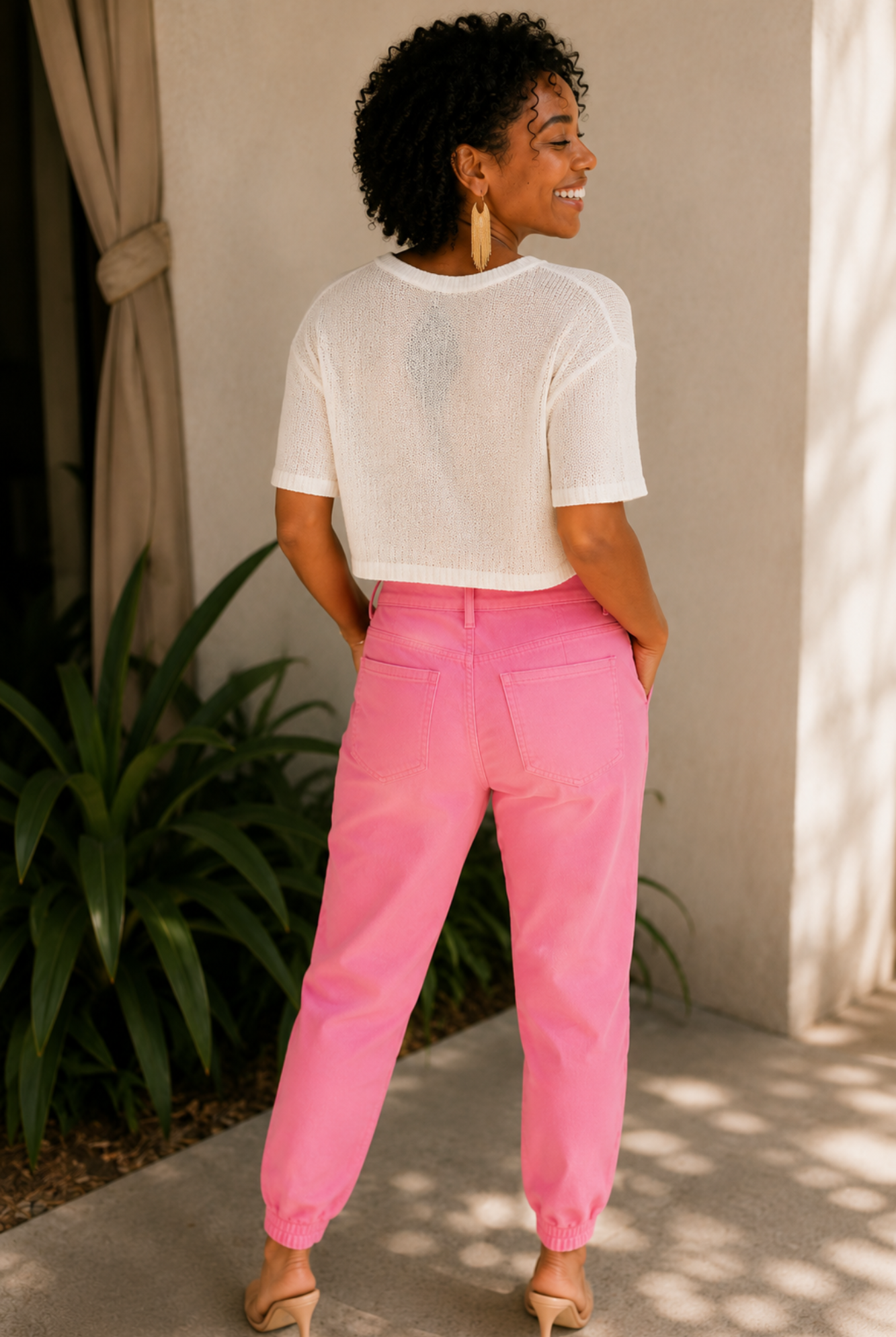 Woman wearing a white top and pink pants standing outdoors.