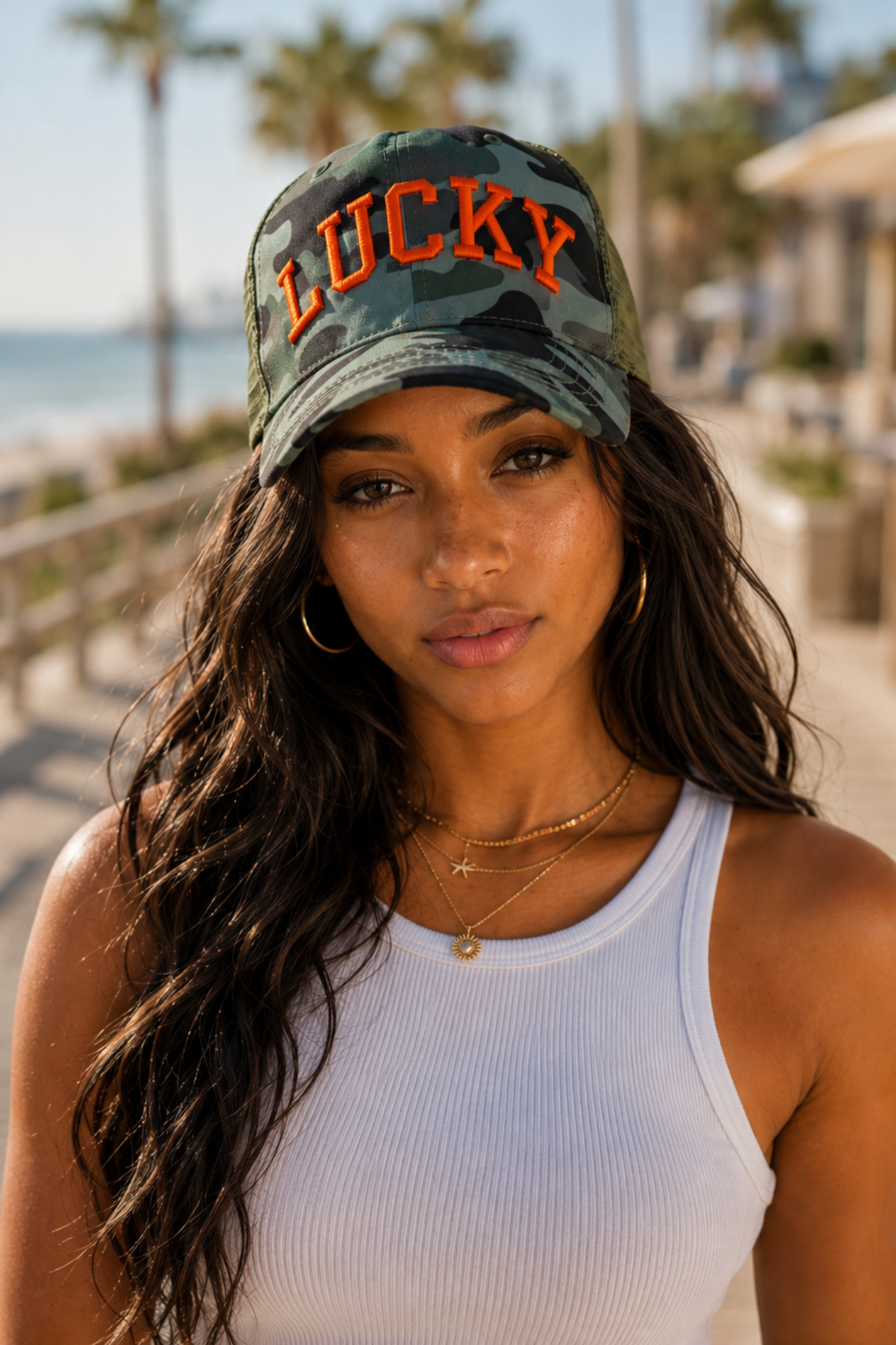 Woman wearing a cap with 'LUCKY' text on a beach boardwalk