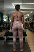 Person in a gym wearing a metallic outfit holding dumbbells.