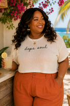 Woman wearing a 'dope soul' shirt by a tropical beach setting