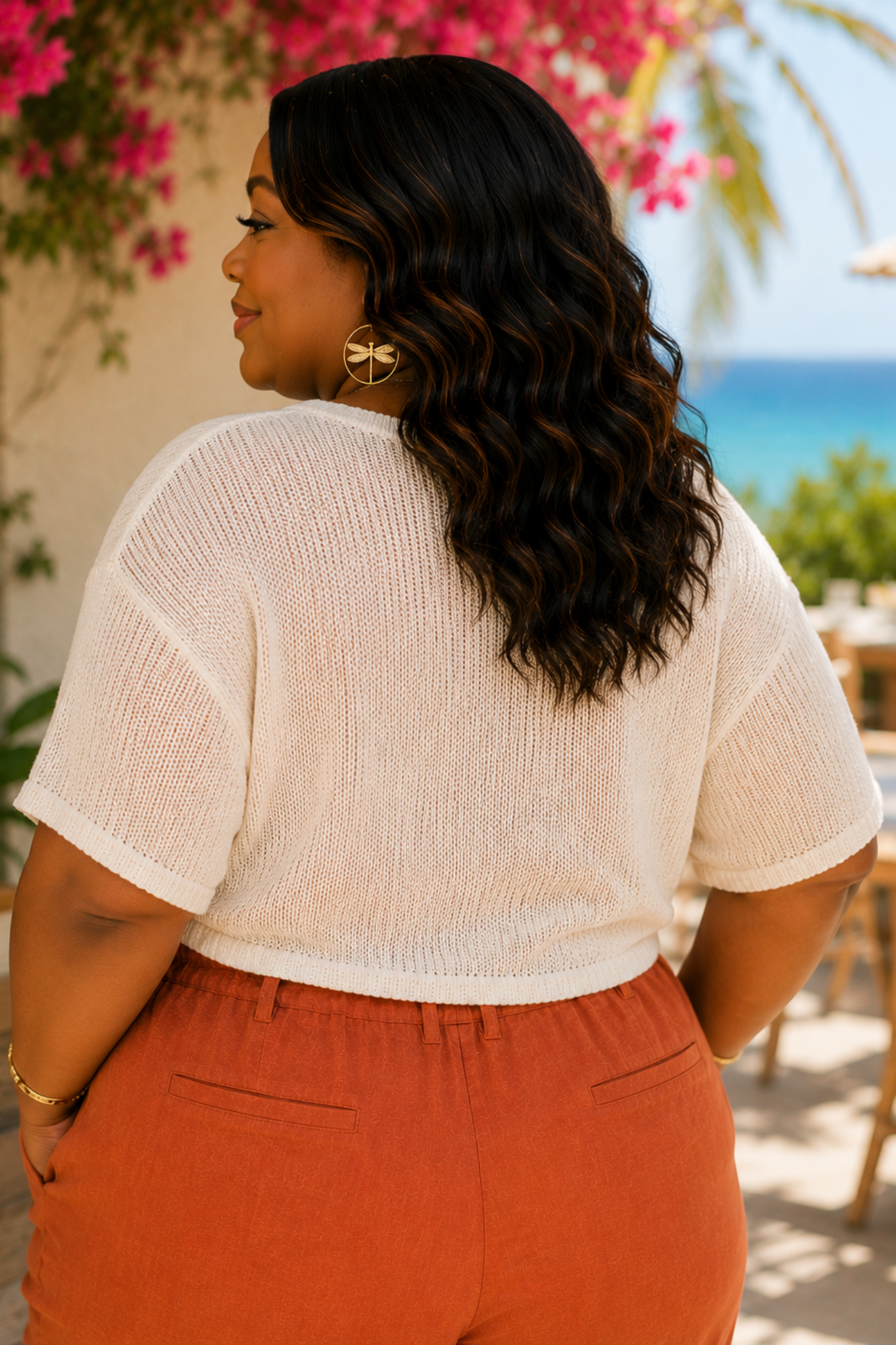 Woman wearing a white top and orange pants with a scenic background